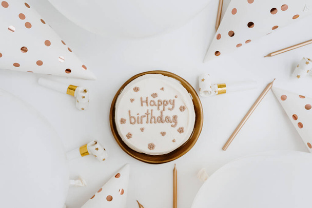 Pose plate avec gâteau d'anniversaire blanc et or, ballons, chapeaux de fête, bougies sur la table. Vue de dessus fête fête fête événement concept célébration - Photo, image