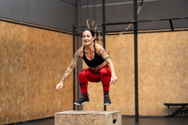 Mature woman exercising jumping into box in a cross training gym - Photo, Image