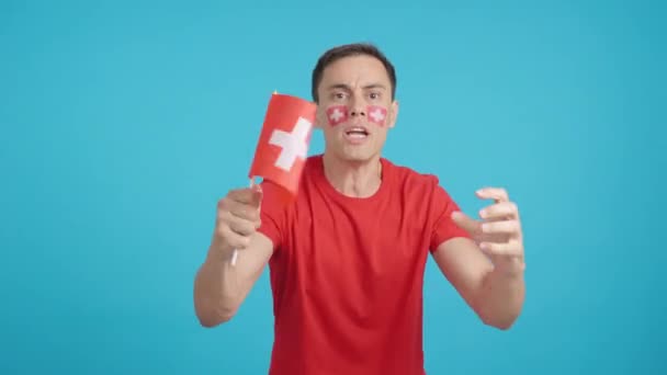 Video en estudio con el croma de un hombre ondeando una bandera nacional suiza enojado con una decisión árbitros - Metraje, vídeo