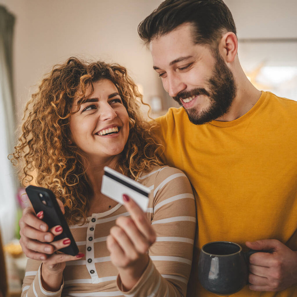 Para kaukaski mężczyzna i kobieta mąż i żona lub chłopak i dziewczyna używają telefonu komórkowego i karty kredytowej zakupy online kupić rzeczy lub zapłacić dokonać rezerwacji płatności e-commerce z domu prawdziwi ludzie - Zdjęcie, obraz
