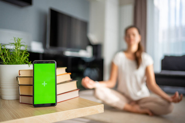 デジタルデトックスコンセプト。 緑色のクロマ キー スクリーンおよび女性が背景で瞑想するスマートフォン. 高品質の写真 - 写真・画像