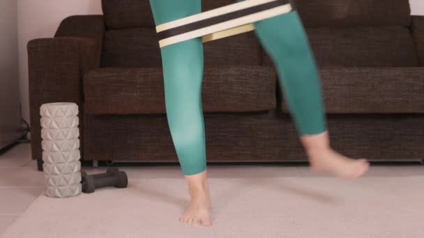 Fitness thuis. Jonge vrouw in panty doet thuis yoga. Sportief meisje in panty doet een workout in de huiskamer.Meisje doet oefeningen met een fitnessband in de kamer.Sportief concept thuis. Hoog - Video