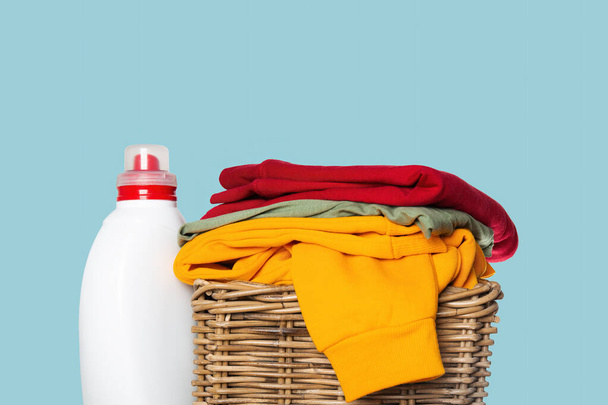 Tętniący życiem stos złożonego prania z czerwoną, zieloną i żółtą paletą, wraz z butelką detergentu do prania. - Zdjęcie, obraz