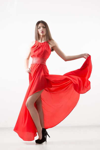 Νεαρή όμορφη γυναίκα με φτερουγισμένο κόκκινο φόρεμα. - Φωτογραφία, εικόνα