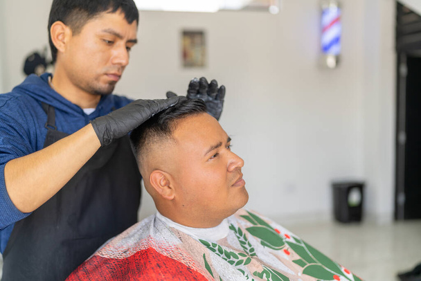 Peluquero aplica gel de peinado al cabello recién cortado de un cliente - Foto, Imagen