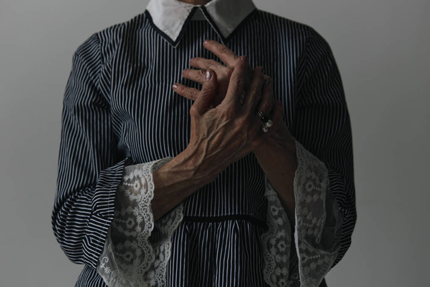 Ältere Frau in gestreiftem Kleid posiert mit den Händen auf der Brust und blickt in die Kamera - Foto, Bild