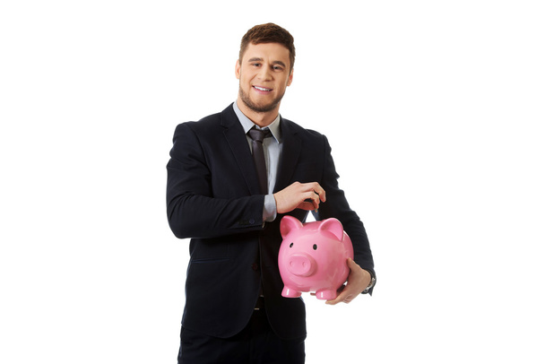Businessman holding a piggybank. - Zdjęcie, obraz