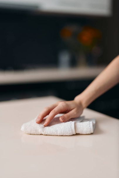 Mesa de cocina blanca de limpieza manual para mujer, eliminación de suciedad y masa húmeda con paño, creación de pan casero fresco - Foto, Imagen
