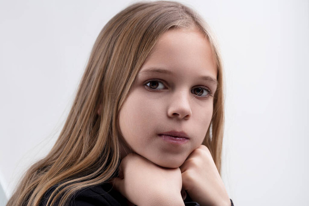 Retrato de una joven pensativa, las manos apoyadas en su barbilla, exudando una serena calma - Foto, imagen