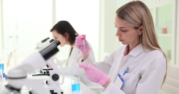 集中した女性科学者は,ピペットブルーの液体をペトリ皿に落とします. サンプルを検査し,実験スローモーションを実施 - 映像、動画