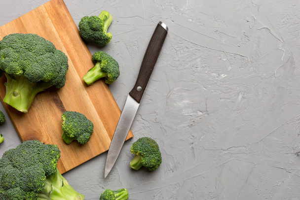 fresh green broccoli on wooden cutting board with knife. Broccoli cabbage leaves. light background. Flat lay. - Photo, Image