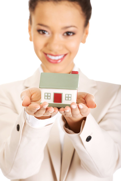 Businesswoman holding small house on palm. - 写真・画像