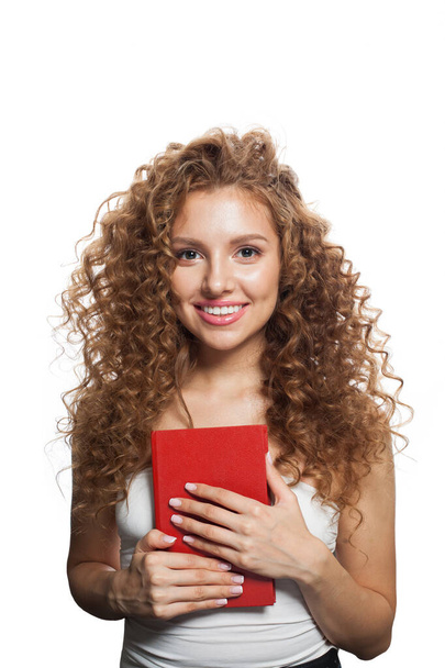 Kaunis onnellinen nuori aikuinen nainen hymyilee ja pitää kirjaa punainen tyhjä kansi eristetty valkoisella taustalla - Valokuva, kuva