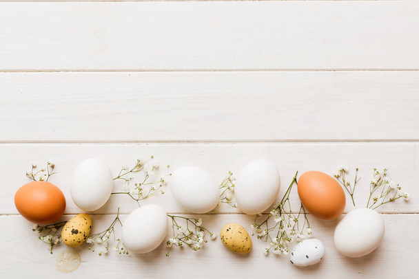 Veselé Velikonoce. Velikonoční vajíčka na barevném stole s gypsophilou. Přírodní barvené barevné vejce pozadí horní pohled s kopírovacím prostorem. - Fotografie, Obrázek