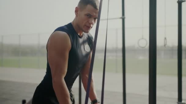 Молодой человек с мускулистым телом тренируется в открытом спортзале со спортивным инвентарем. Культурист мужчина делает упражнения и тренировки мышц рук снаружи. Концепция - Кадры, видео