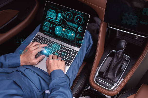 Un professionnel en costume bleu interagit avec une interface de voiture olographe de haute technologie sur un ordinateur portable à l'intérieur d'un véhicule - Photo, image