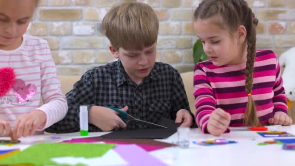 Lindos niños pequeños cortando papel de color con tijeras en el escritorio en el jardín de infantes. Actividades lúdicas. Imágenes de alta calidad 4k - Imágenes, Vídeo