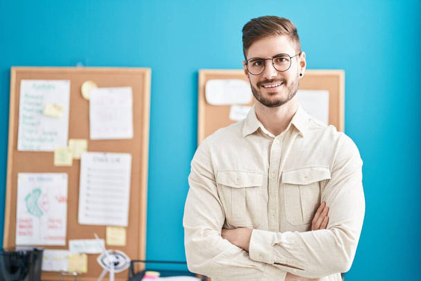 Mladý běloch muž obchodní pracovník s úsměvem sebevědomí stojící s rukama zkřížené gesto v kanceláři - Fotografie, Obrázek
