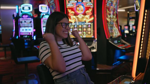 Mujer joven emocionada celebrando una victoria en las máquinas tragamonedas de casino. - Foto, imagen