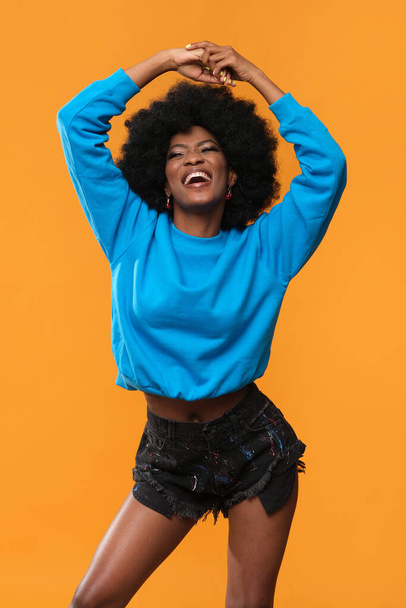 Χαρούμενη Αφρο-Αμερικανίδα με μπλε μπλούζα. - Φωτογραφία, εικόνα