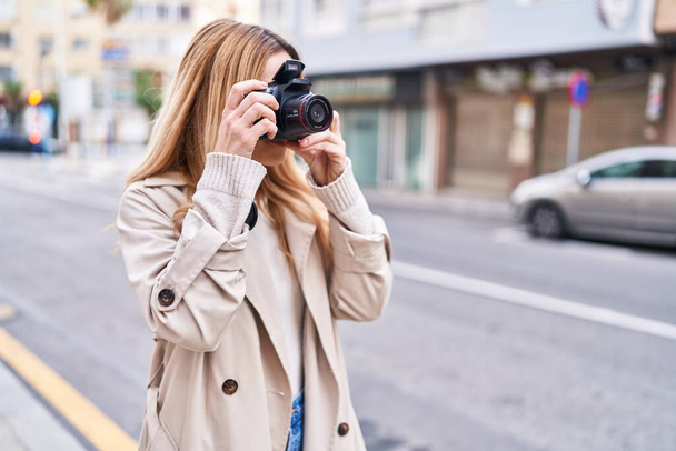 Giovane donna bionda che fa uso di macchina fotografica professionale in strada - Foto, immagini
