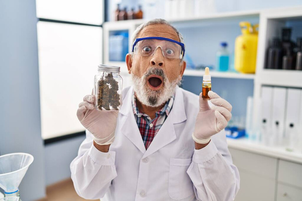 Zszokowany starszy pan patrzy w zdumiewającym strachu na marihuanę medyczną w laboratorium, jego ekspresyjna twarz jest mieszanką zaskoczenia i podniecenia. - Zdjęcie, obraz