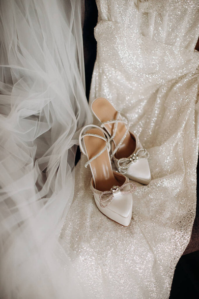 Белая мода бренд свадебные туфли невесты украшены блестками на блестящее свадебное платье крупным планом - Фото, изображение