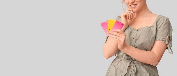 Junge Frau mit Kreditkarten auf hellem Hintergrund mit Platz für Text - Foto, Bild
