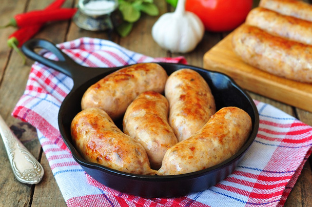 Fried chicken sausages with vegetables on a frying pan - Photo, Image