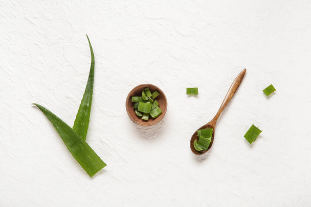 Cucchiaio e ciotola con foglie di aloe tagliate su sfondo bianco - Foto, immagini
