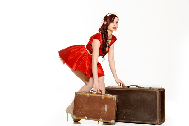 Beautiful woman in a red dress  with retro suitcase posing on a white background   - Fotografie, Obrázek