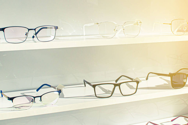 экспонент бокалов, состоящих из полок модных очков, показанных на стене в оптическом магазине
  - Фото, изображение