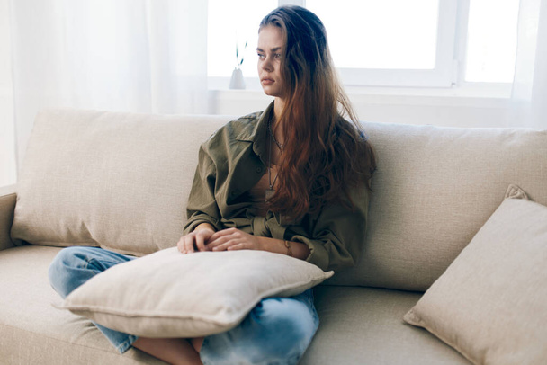 Aggódó nő ül egy kanapén, szomorúság és stressz - ábrázolása mentális egészségügyi problémák otthon beállítása - Fotó, kép