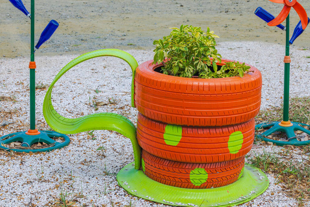 Näkymä elinvoimainen kukkapenkki suunniteltu kuten kahvikuppi, valmistettu vanhoista, käyttökelvoton auton renkaat, täynnä trooppisia kasveja. Curacao. - Valokuva, kuva