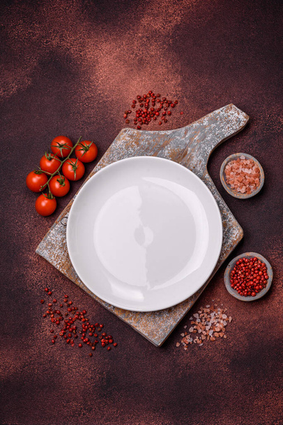 Empty ceramic round plate on dark textured concrete background. Cutlery, preparation for dinner - Фото, изображение