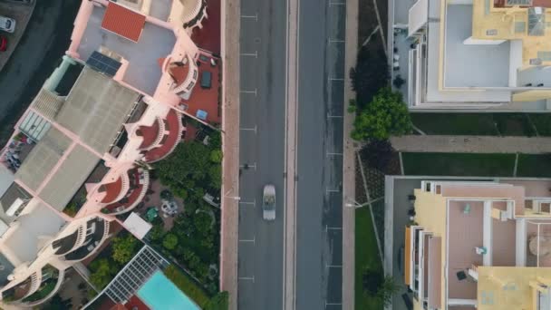 Drónra néző városi utcában aszfalt út fut között lakóépületek. Autók száguldanak kifelé a városi úton. Hangulatos mediterrán város kerületi top shot. Autók közúti közlekedésben. - Felvétel, videó