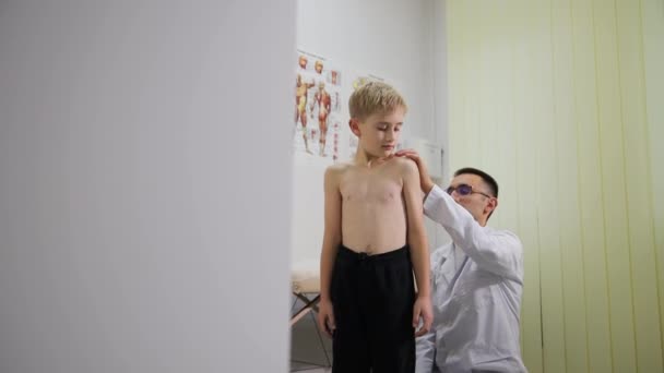 Ortopedický lékař vyšetřuje záda malého chlapce. Léčba dětí. Dětský lékař. - Záběry, video