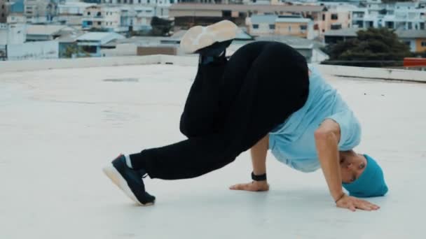 Profesyonel beyaz dansçı, şehir ya da şehirle çatıda sokak dansı yapıyor. Genç adamın sokak dansı yaparken dondurucu poz vermesi. Açık hava sporu 2024 hiphop.. - Video, Çekim