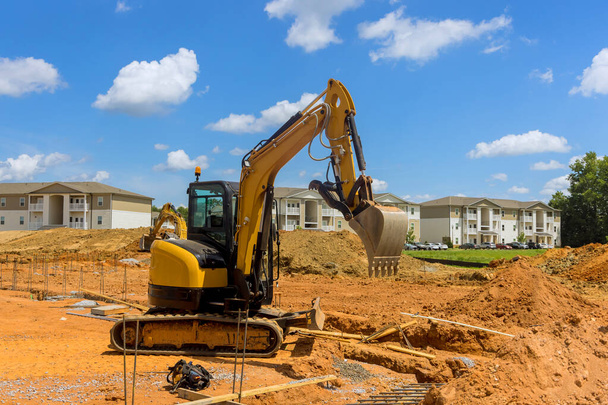 Excavadoras excavan trincheras en el sitio de construcción durante las obras de movimiento de tierras que preparan el área de infraestructura - Foto, Imagen