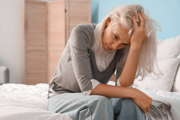 Депрессивная зрелая женщина сидит в спальне - Фото, изображение