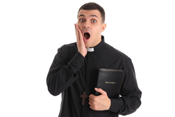 Scioccato giovane sacerdote con Sacra Bibbia su sfondo bianco - Foto, immagini