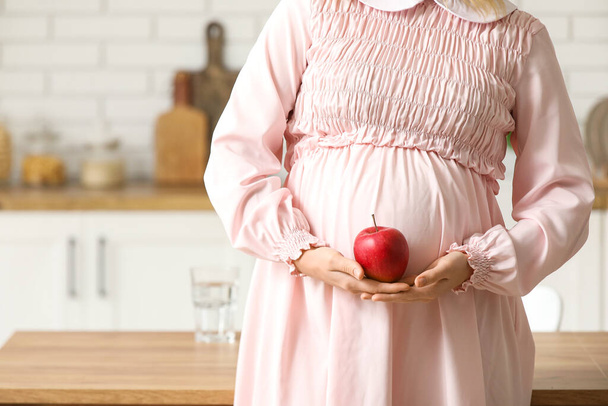 Nuori raskaana oleva nainen omena keittiössä, lähikuva - Valokuva, kuva