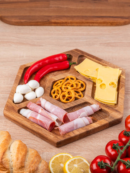 Ассорти из мяса, сыра и овощей - подается на деревянной доске с помидорами и хлебом - Фото, изображение
