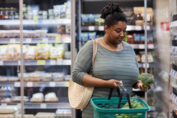 Tailliertes Porträt einer echten schwarzen Frau, die frisches Gemüse im Supermarkt kauft, Kopierraum - Foto, Bild