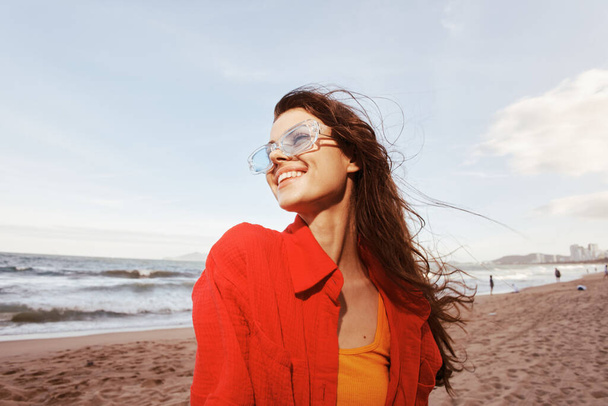 Lächelnde Frauen Freudige Emotion bei buntem Sonnenuntergang: Porträt eines trendigen, sorgenfreien Models, das Freiheit und Urlaub am Strand des Ozeans genießt - Foto, Bild