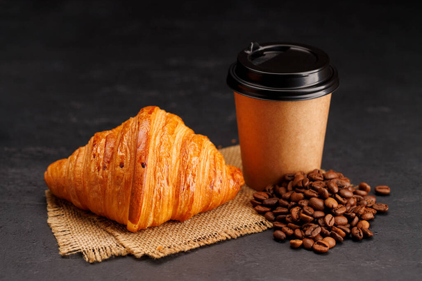 Aromatischer Kaffee in einer Papptasse gepaart mit einem flockigen Croissant. Mit Kopierraum - Foto, Bild