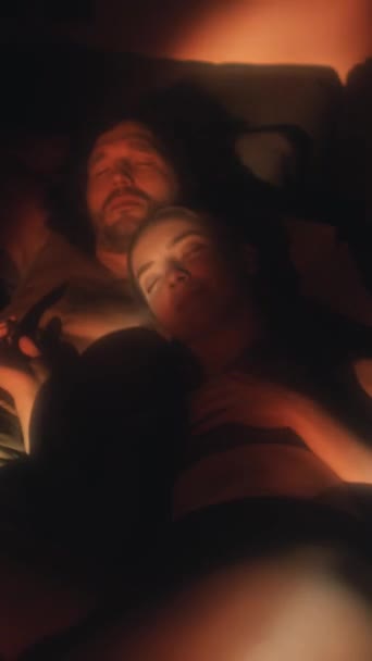 Függőleges felvétel fiatal romantikus barát és barátnő ölelés az ágyban sötét szobában vetített tűz lángok - Felvétel, videó