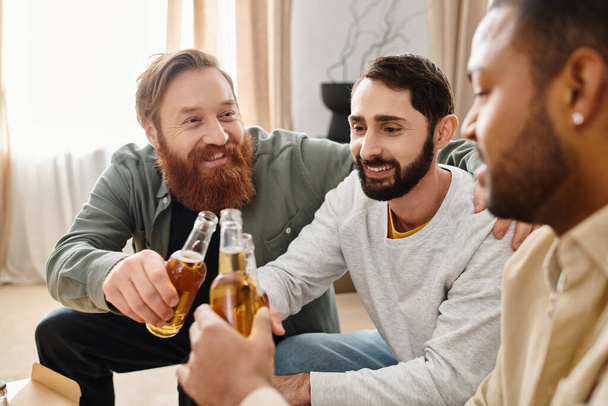 Drie knappe, vrolijke mannen van verschillende rassen genieten van bier en goed gezelschap thuis, bevorderen vriendschap en gelach. - Foto, afbeelding