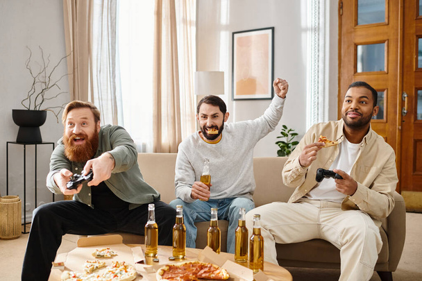 Trzech przystojnych, międzyrasowych mężczyzn w luźnych ciuchach siedzi przy stole z pizzą i piwem, śmiejąc się i świetnie się bawiąc. - Zdjęcie, obraz