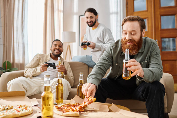 Три красивых межрасовых мужчины наслаждаются пиццей и пивом на случайном собрании, делятся смехом и хорошо проводят время за столом. - Фото, изображение